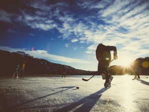 Hockey players on a frozen lake at sunset.