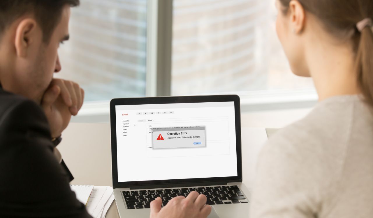 Two people look at an error message on a laptop.
