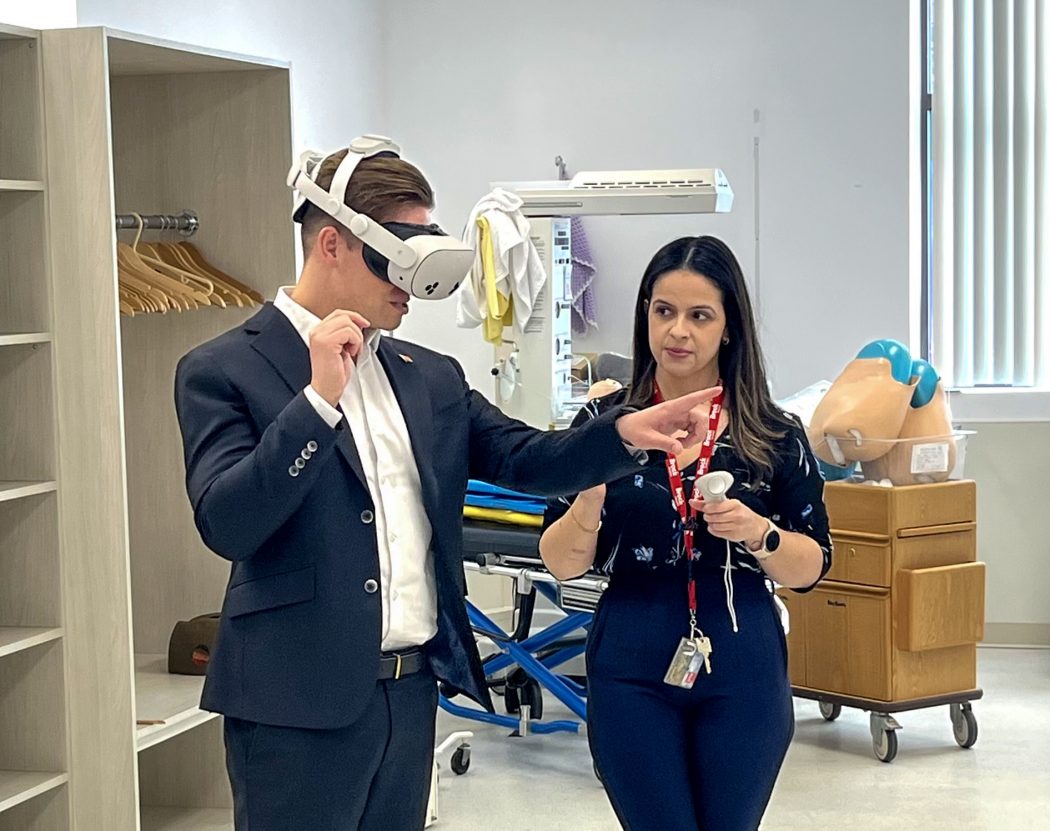 A man uses a VR headset while a woman in scrubs provides instructions.