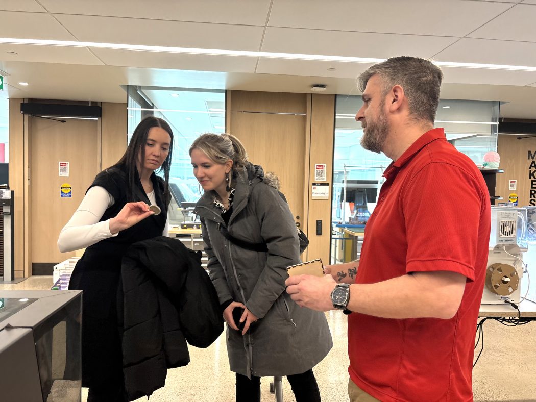 Three people look at an object.
