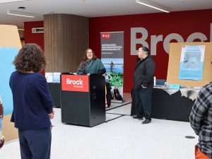 A woman speaks to an audience from behind a podium.