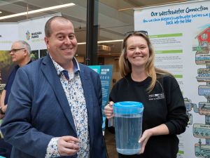 A man holding a glass stands beside a woman holding a jug of water,