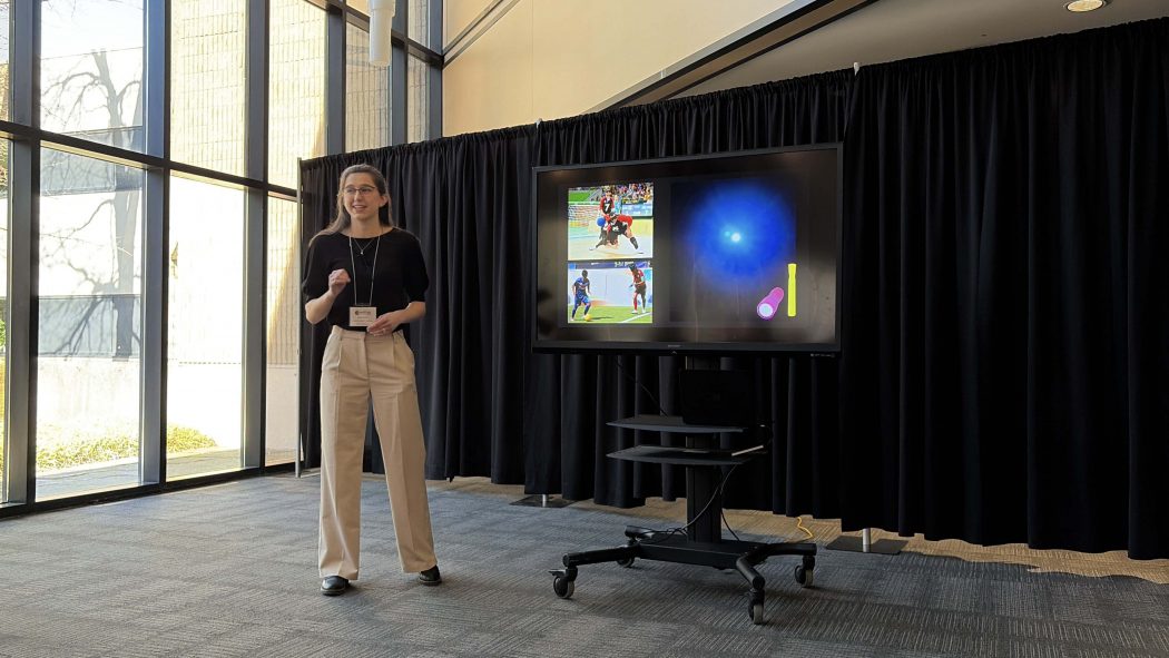 A young woman makes a presentation beside a screen.