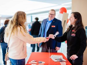 A person gets a brochure from an employee at a university information fair.