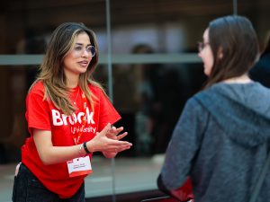 Two people have a conversation at a university information fair.