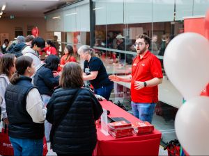 A man speaks to a group of guests at a university information fair.