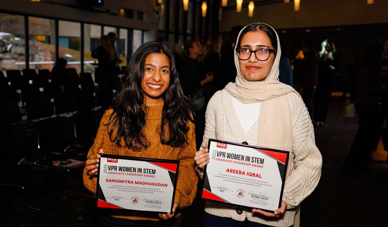 Two women stand holding awards.