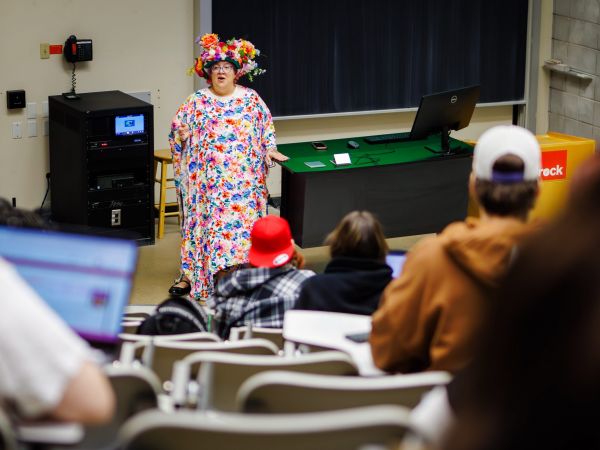 Robyn Bourgeois wearing a crown of flowers and colourful flowered dress at the front of the classroom in October 2025.