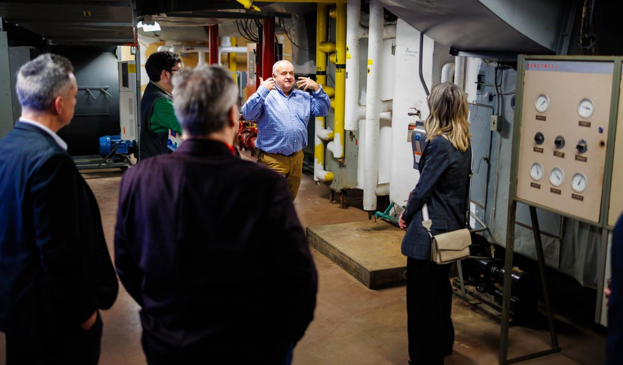 A group of people tour a utilities area in a university.