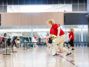 People play pickleball in a gym.