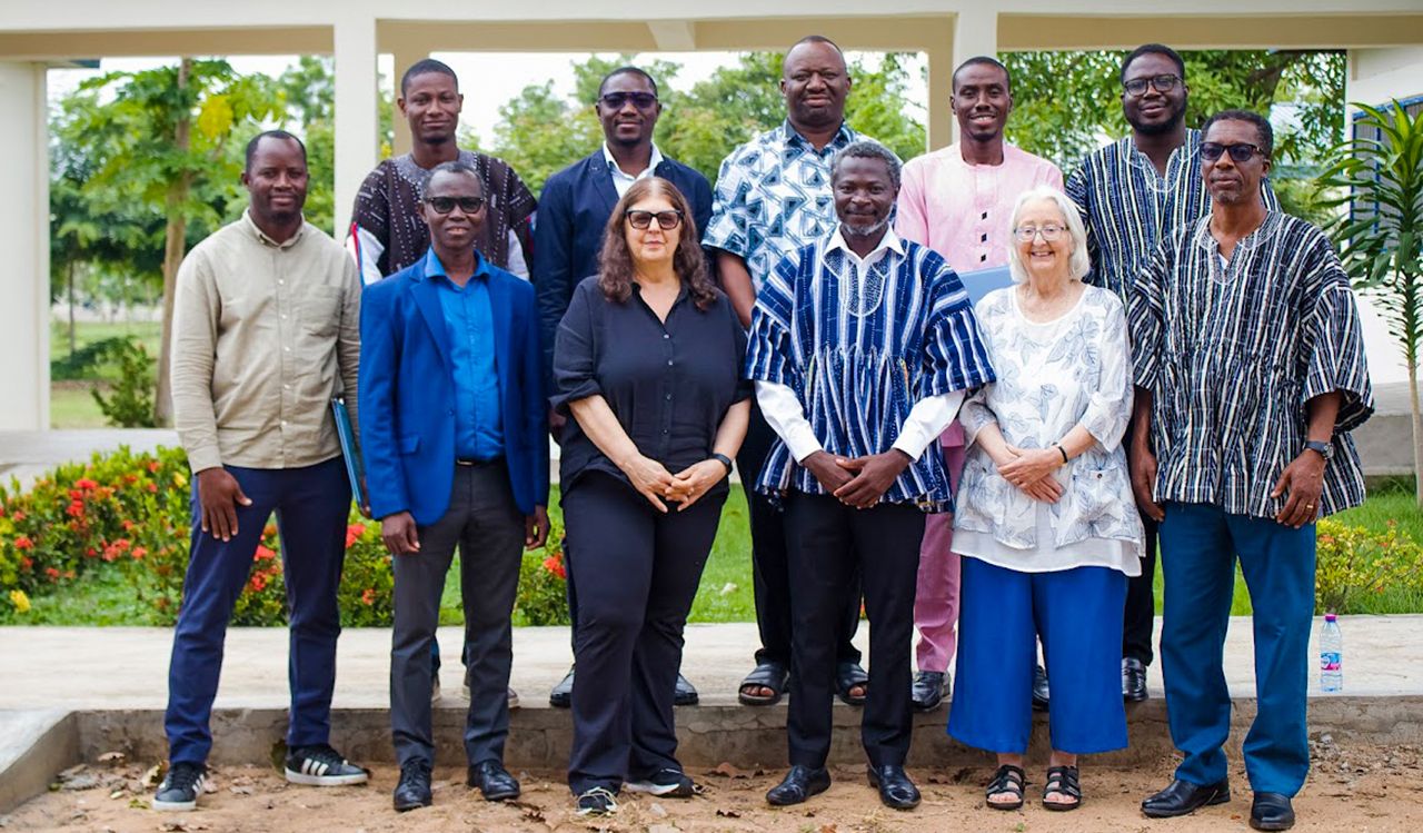 A large group of people pose for a photo outside with a garden behind them.
