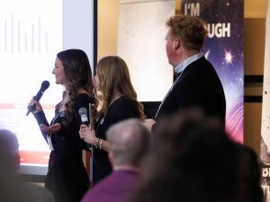 Three university students speak to an audience during a panel discussion.