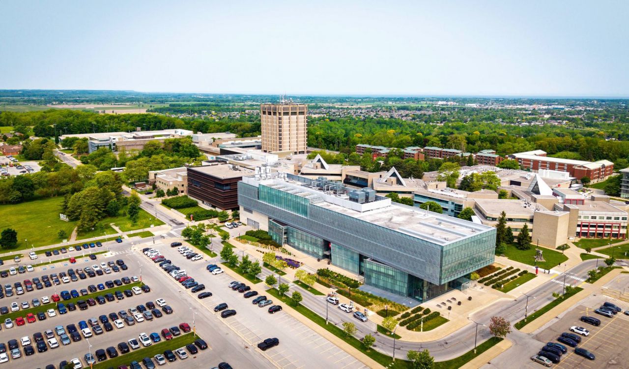 A wide view of Brock University’s main campus, featuring modern campus buildings beneath a bright blue sky.