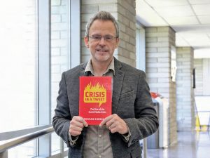 Duncan Koerber holds his new book, Crisis in a Tweet.