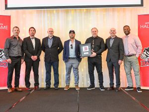 A group of men pose with an award on stage.