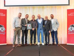 A group of men pose with an award on stage.