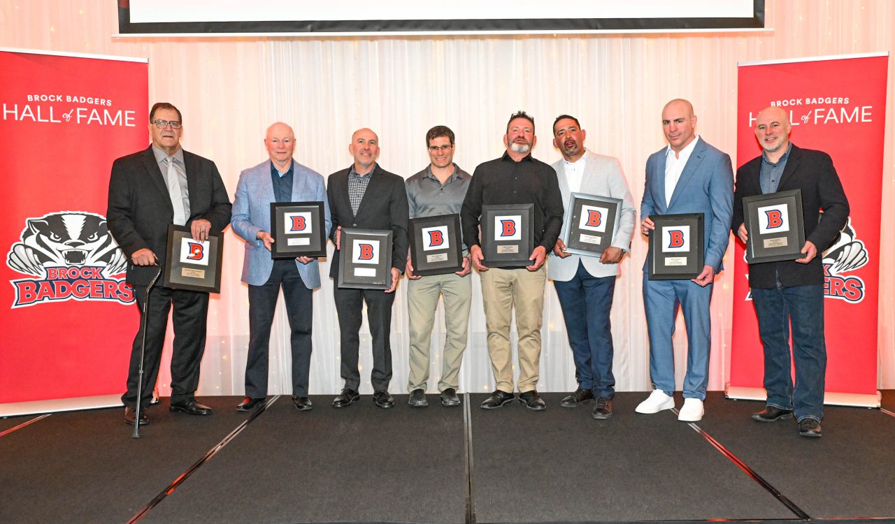 A group of men pose with awards on stage.