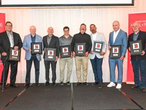 A group of men pose with awards on stage.