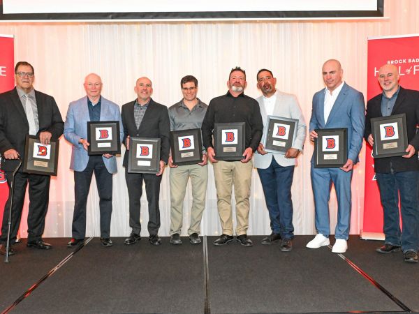 A group of men pose with awards on stage.