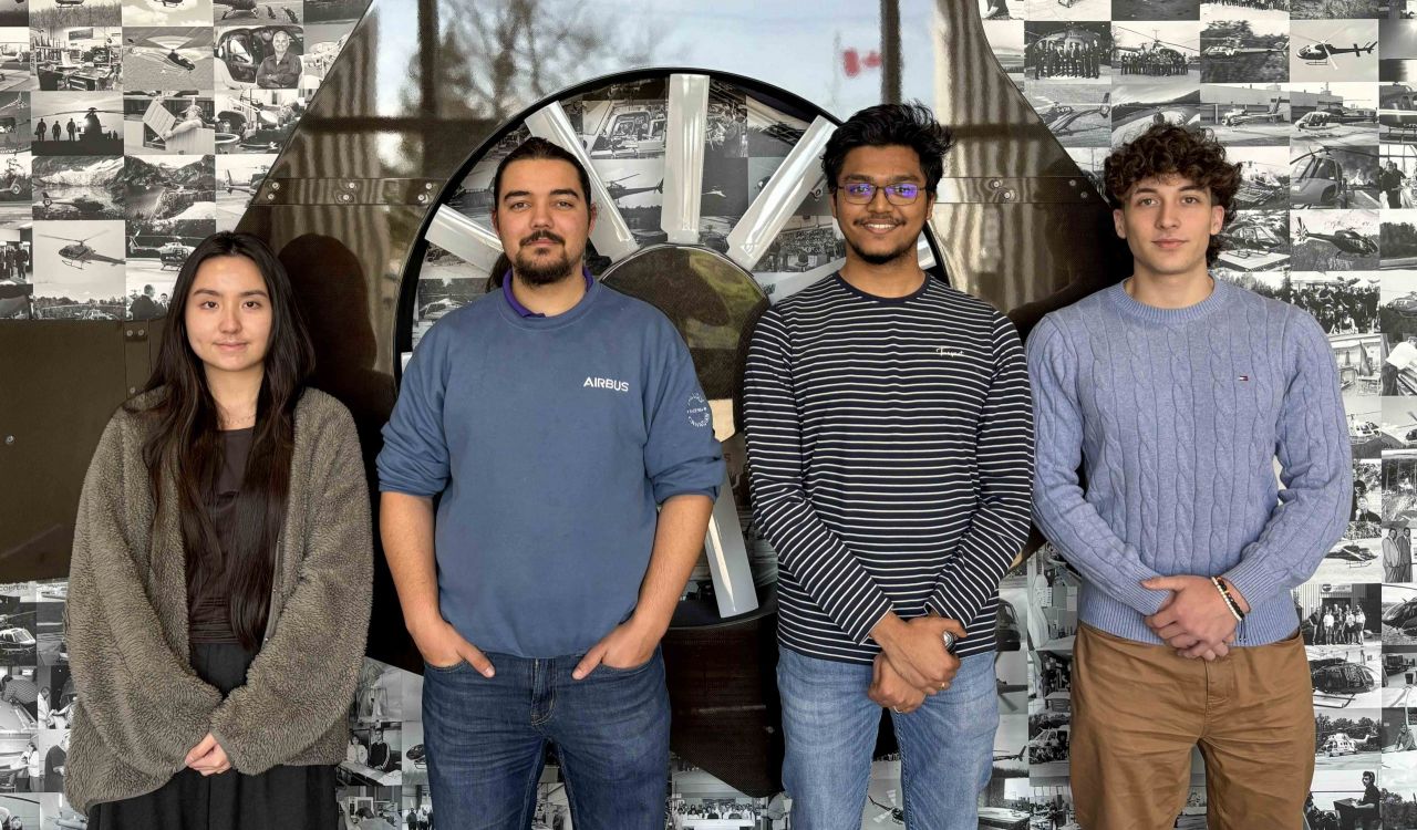 Group of students stand in a row in front of a wall.
