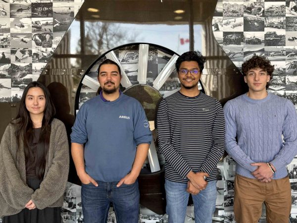Group of students stand in a row in front of a wall.