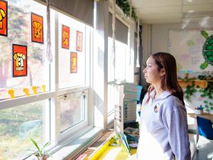 Person stands and looks at a window that has pictures of orange t-shirts taped onto it.