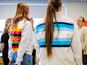 Students stand backward to showcase their sweatshirts that have traditional ribbon designs on them.