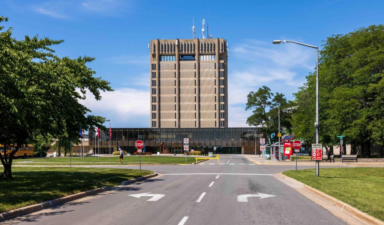 A roadway leads to a large concrete and glass building.
