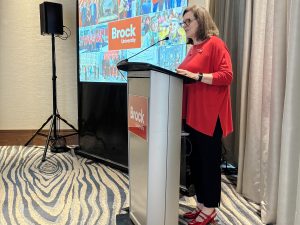 A woman stands at a podium speaking.