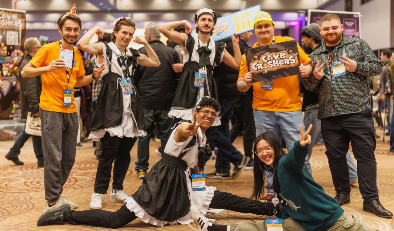 A group of students wearing various costumes, some dressed like maids, stand together in various poses smiling at the camera.