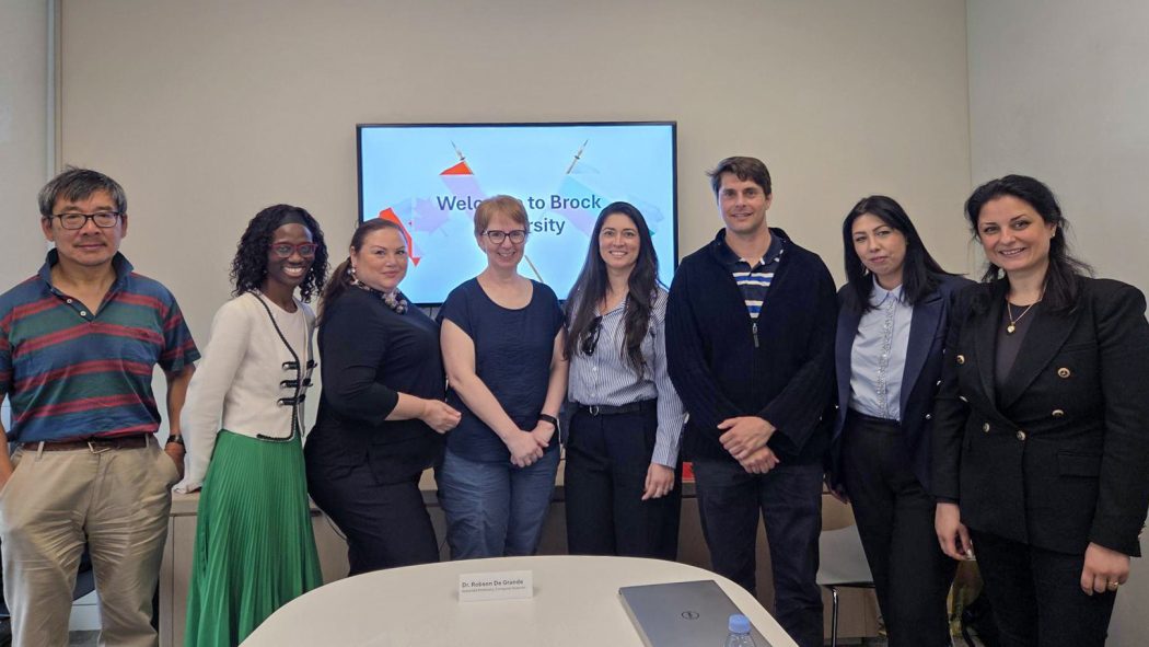 A group of people pose for a photo in front of a presentation screen in a meeting room.