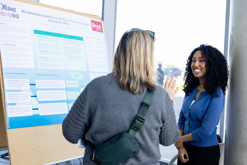 Two people look at a research poster while talking.