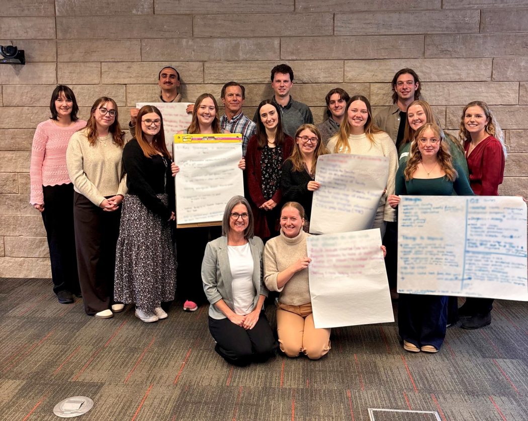 Group photo of Brock students and staff holding chart paper.