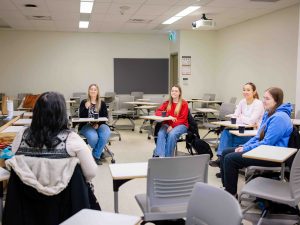 People sit in a circle at desks and talk.