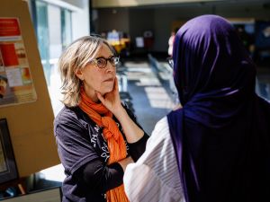 Two attendees have a conversation beside a poster display during a Health, Art and Justice Lab event.