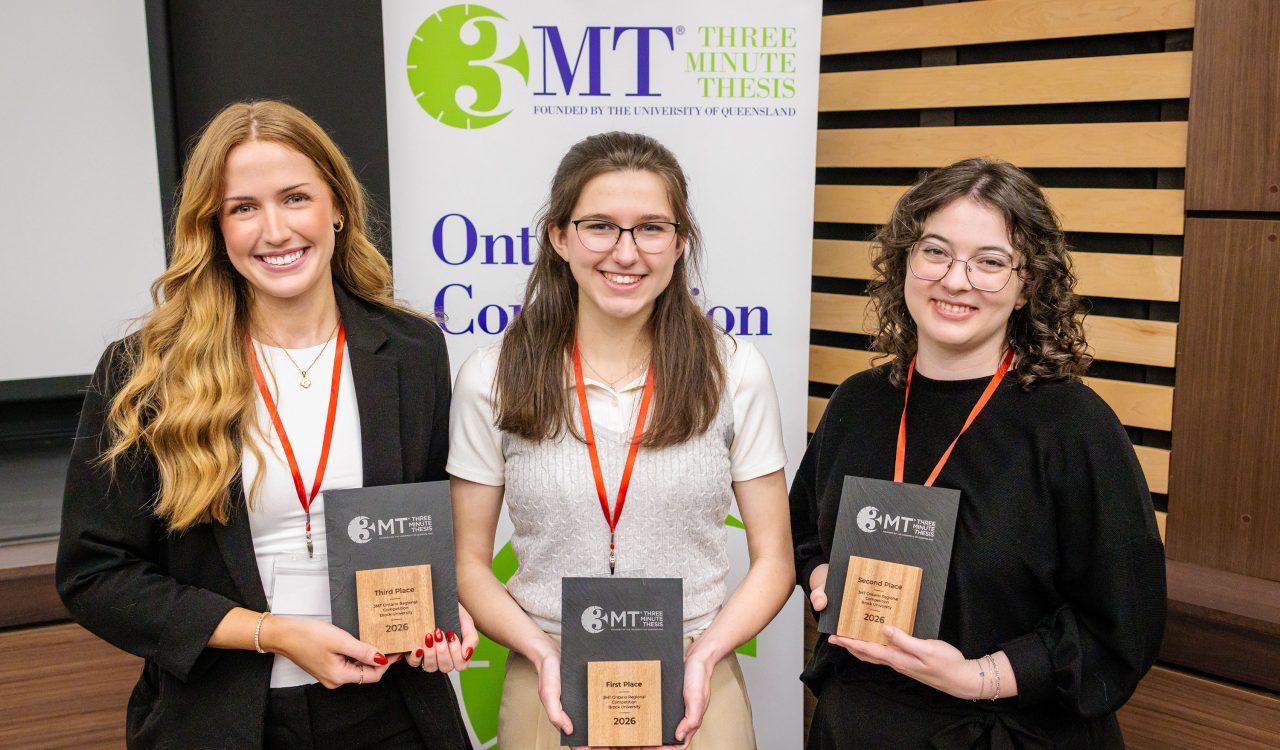 Three women stand together holding awards.