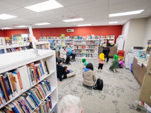 Children and adults listen to a woman read at a library story time event.