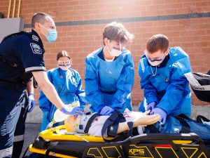 Nursing students and a Niagara EMS paramedic provide simulated care to a mannequin on a stretcher during a Code Orange exercise.