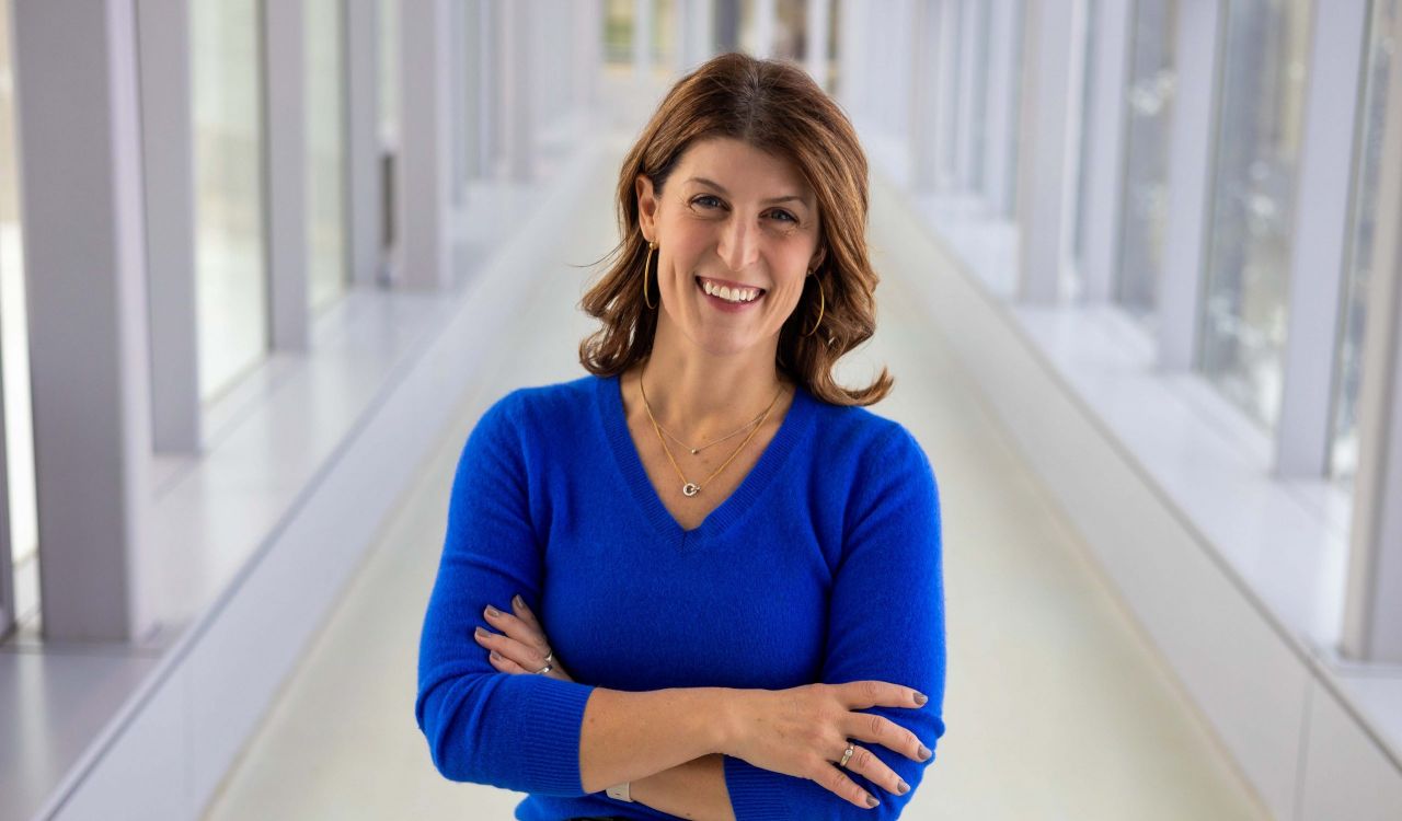 A woman poses for a photo in a sunny hallway.