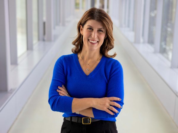 A woman poses for a photo in a sunny hallway.