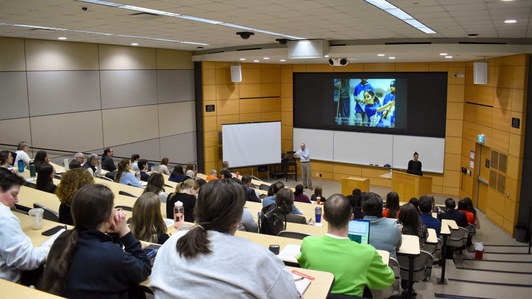 A group of students are listening to keynote address in an auditorium at a conference.