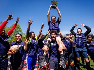 A team of soccer players celebrate and hold up a trophy.