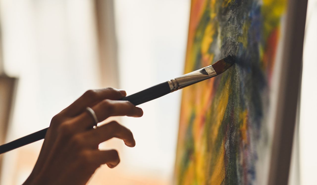 Close-up view of hands painting a canvas.