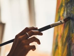 Close-up view of hands painting a canvas.
