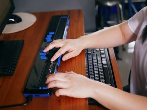 Close-up view of someone typing on a braille keyboard.