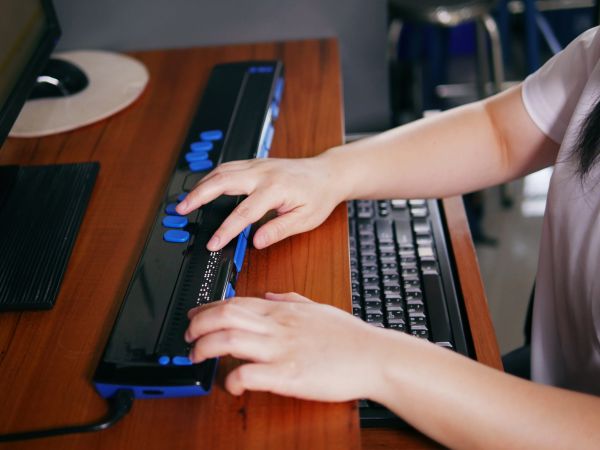 Close-up view of someone typing on a braille keyboard.