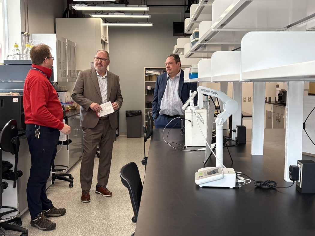 Three people have a conversation in a lab.