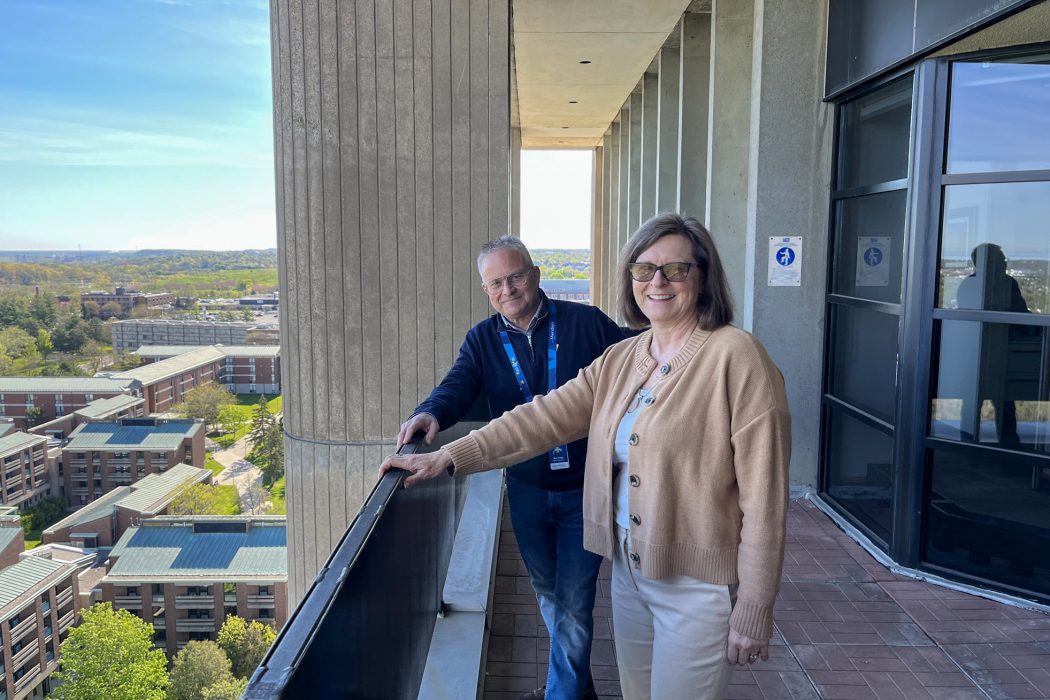 Two people stand on a balcony.
