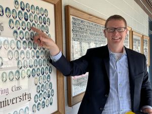 A man looking at his class photo on a university campus.