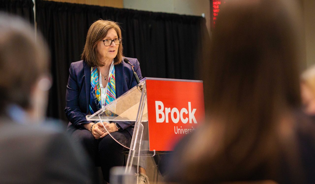 A woman speaks from a podium at an event.